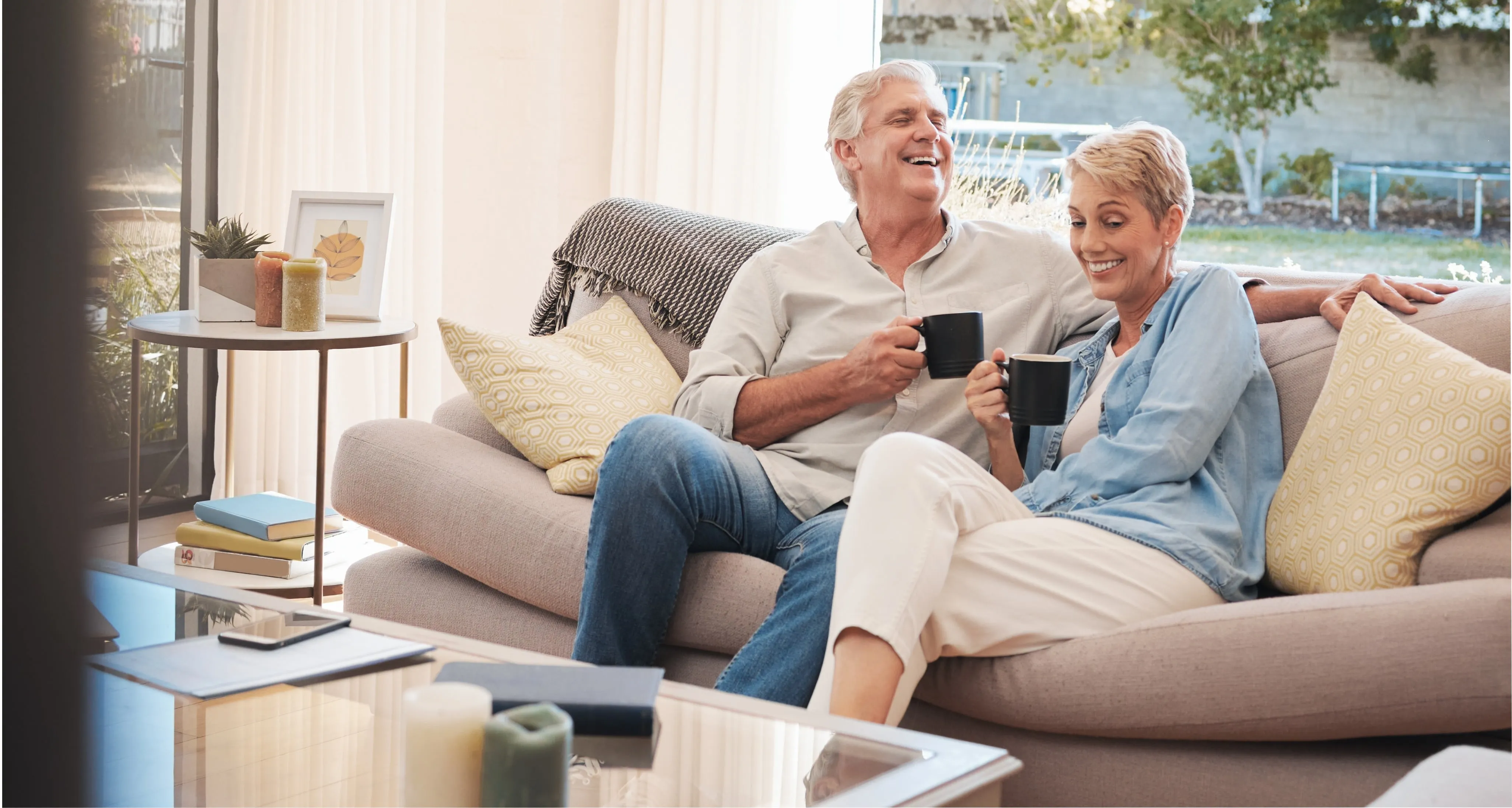 a couple laughing and drinking coffee on the couch
