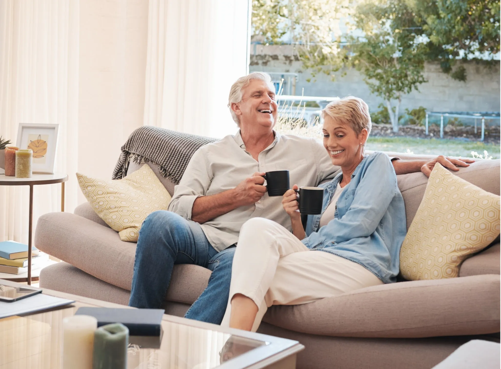 a couple laughing and drinking coffee on the couch